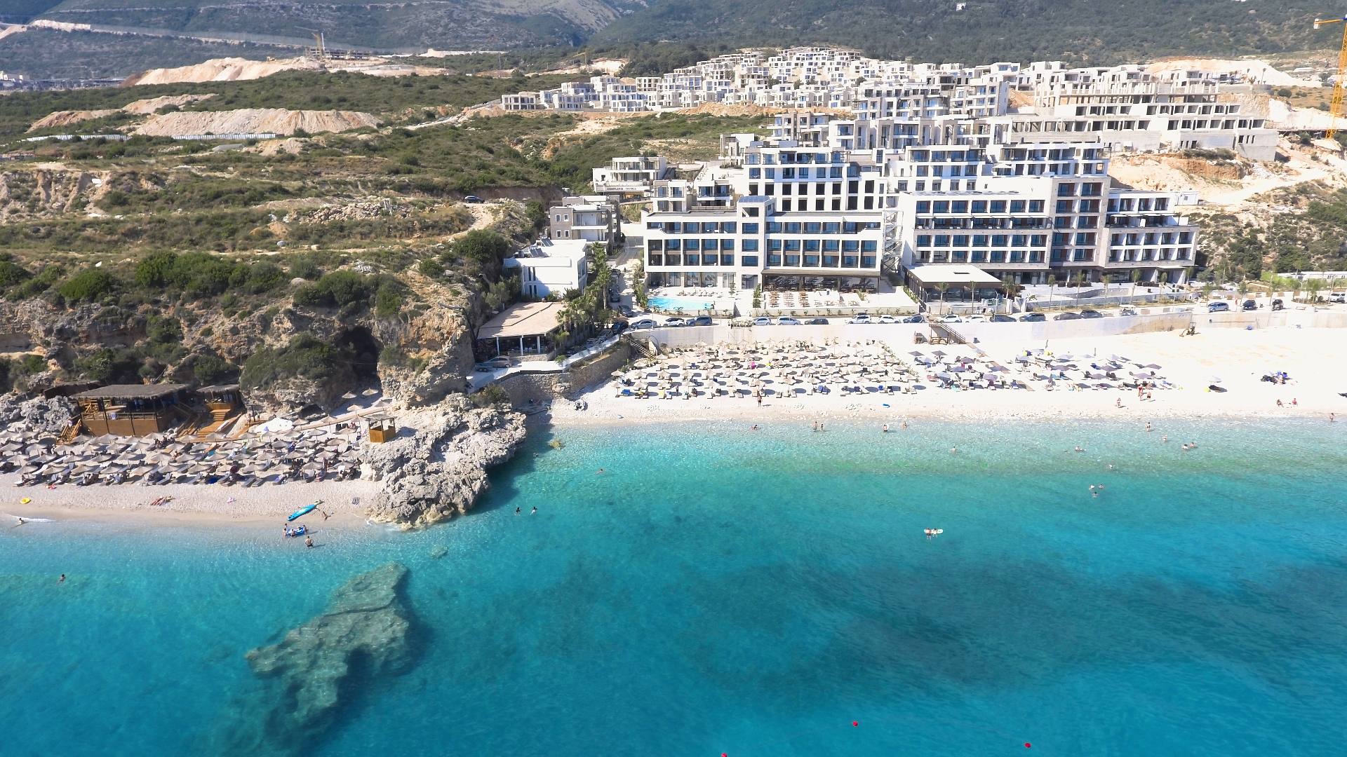 Dhërmi seen from above — stone houses tucked between the mountain and the sea.